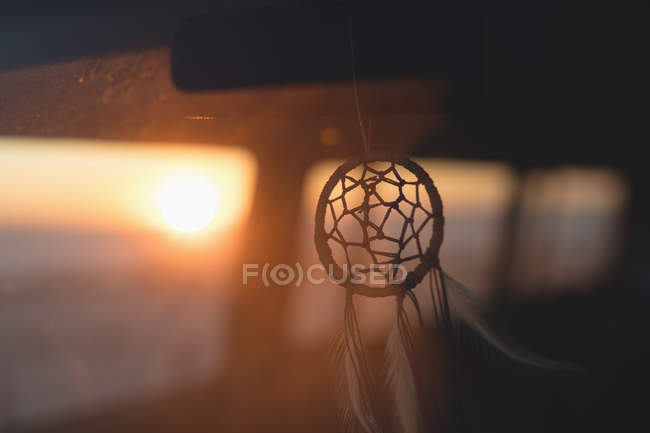 Автомобільний кулон, що висить в машині на заході сонця — стокове фото