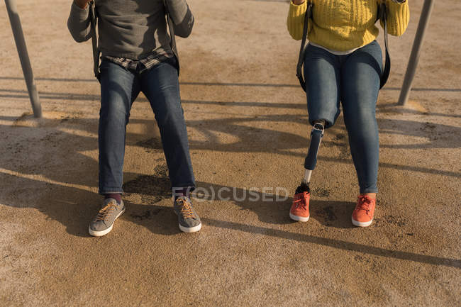 Baixa seção de casal jogando no parque infantil swing — Fotografia de Stock