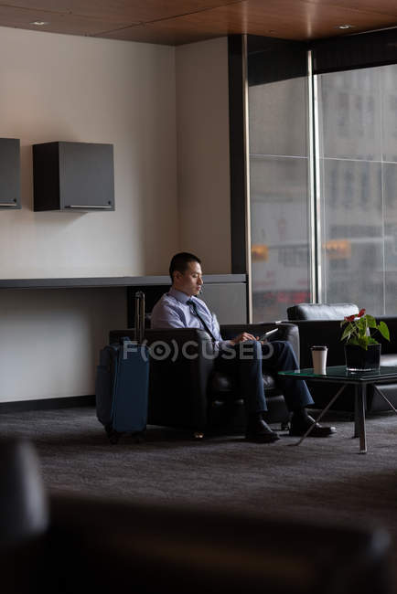 Empresário usando tablet digital no lobby do hotel — Fotografia de Stock