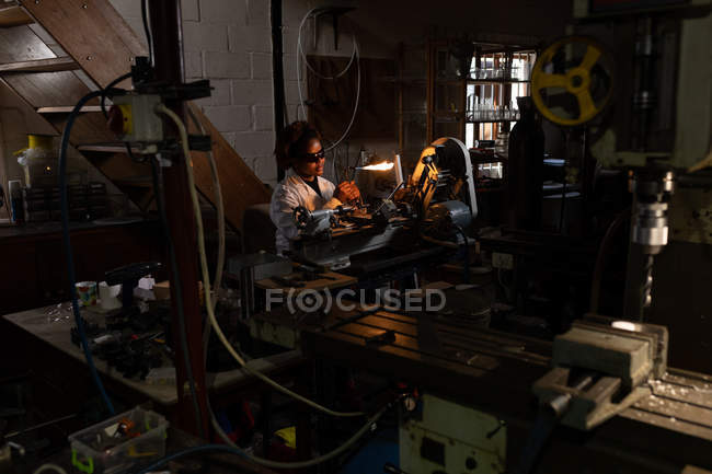 Жінка-працівник використовує зварювальний факел на скляній фабриці — стокове фото