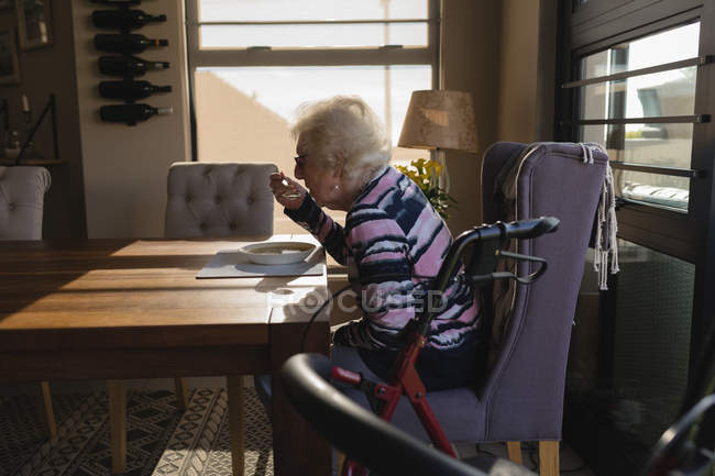 Side view of senior woman having food at home — Stock Photo