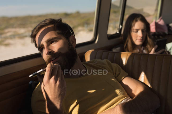 Чоловік використовує мобільний телефон у фургоні під час подорожі — стокове фото