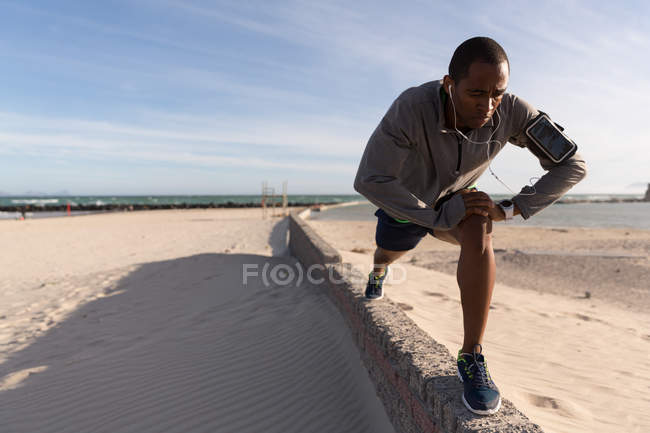 Männlicher Athlet trainiert auf umgebender Mauer in Strandnähe — Stockfoto