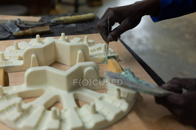 Gros plan du travailleur appliquant de la cire sur le moulage dans un atelier de fonderie — Photo de stock