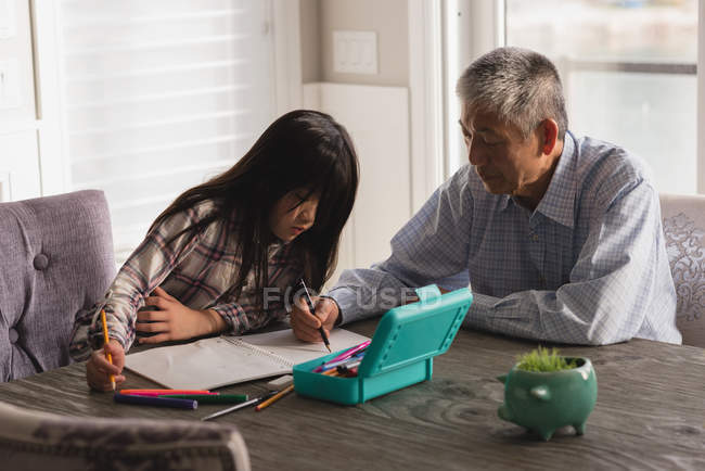 Grandfather and granddaughter drawing sketch on dining table at home — Stock Photo