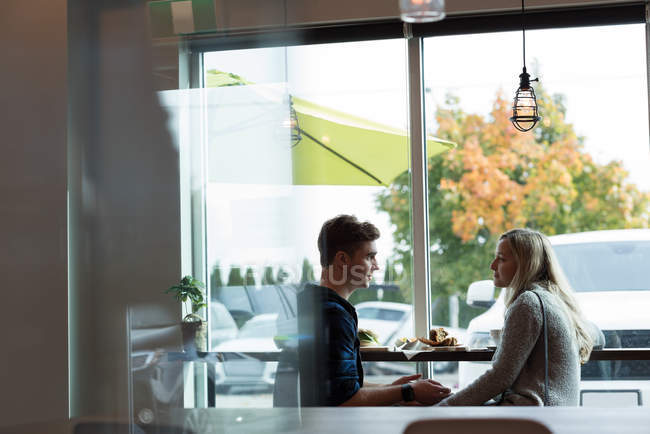 Vista lateral do casal interagindo uns com os outros no café — Fotografia de Stock