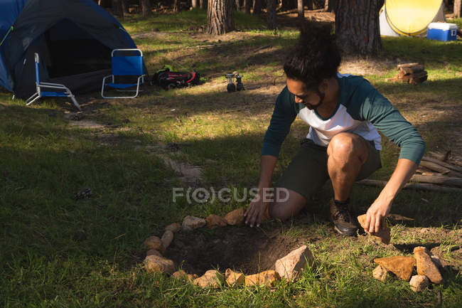 Young man preparing bonfire in the forest — Stock Photo
