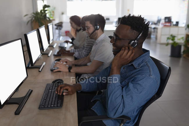 Ejecutivos de servicio al cliente hablando en auriculares en el escritorio en la oficina - foto de stock