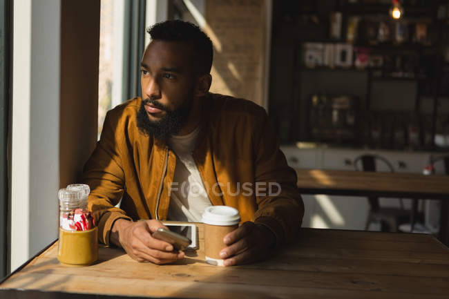 Homem atencioso olhando através da janela no café — Fotografia de Stock
