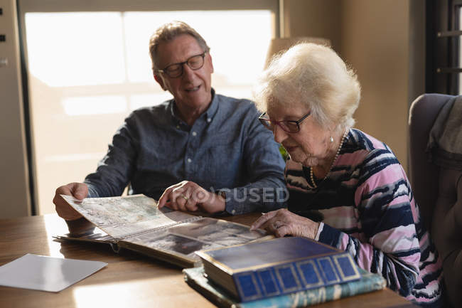 Senior couple looking photo album in living room at home — Stock Photo