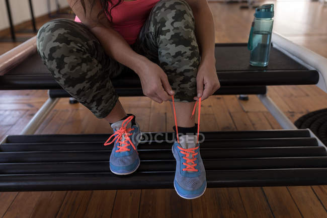 Low section of female boxer tying shoe laces in fitness studio — Stock Photo