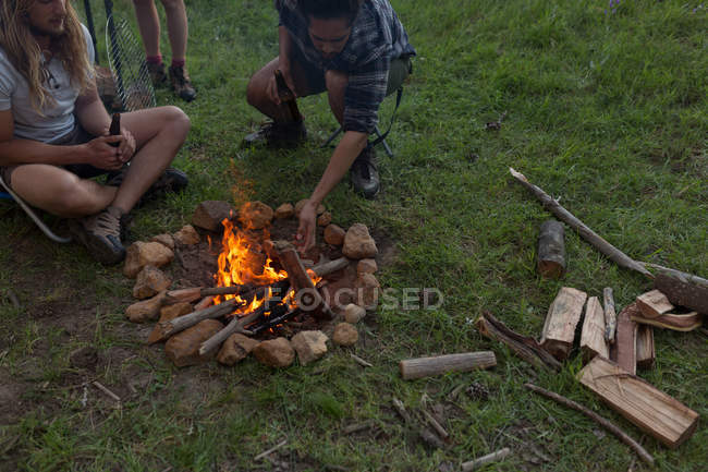 Young men sitting near campfire at campsite — Stock Photo