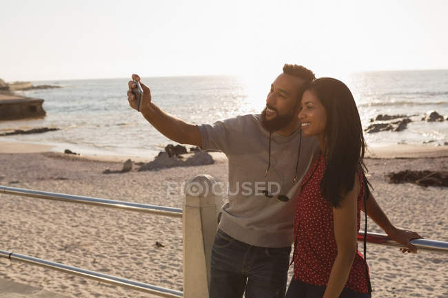 Счастливая пара делает селфи на мобильном телефоне на набережной — стоковое фото