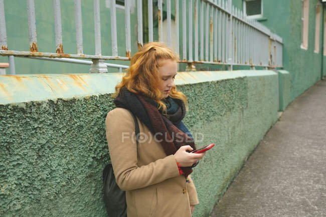 Mulher ruiva usando telefone celular em um beco — Fotografia de Stock