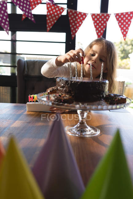 Cute girl placing candle on cake at home — Stock Photo