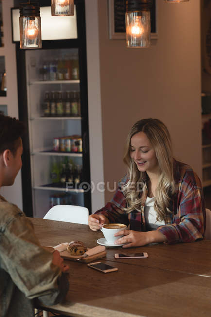 Pareja joven interactuando entre sí en la cafetería - foto de stock