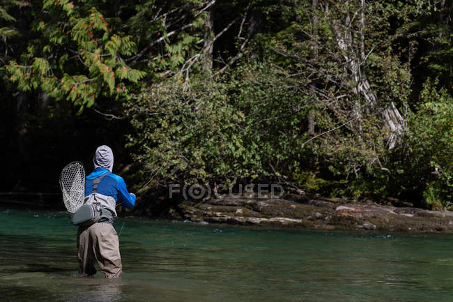 Vista posteriore del pescatore pesca a mosca nel fiume — Foto stock