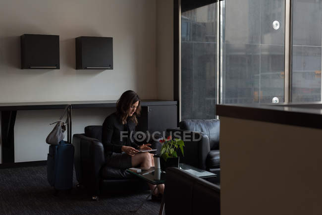 Mujer de negocios usando tableta digital en el vestíbulo del hotel - foto de stock