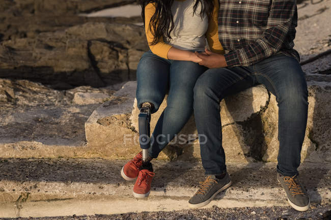 Low section of couple sitting near beach — Stock Photo