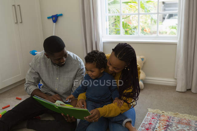 Eltern lesen mit ihrem Sohn zu Hause im Wohnzimmer ein Bilderbuch — Stockfoto