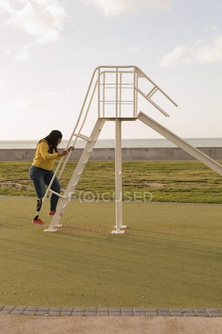 Side view of disable woman ascending on ladder slide — Stock Photo