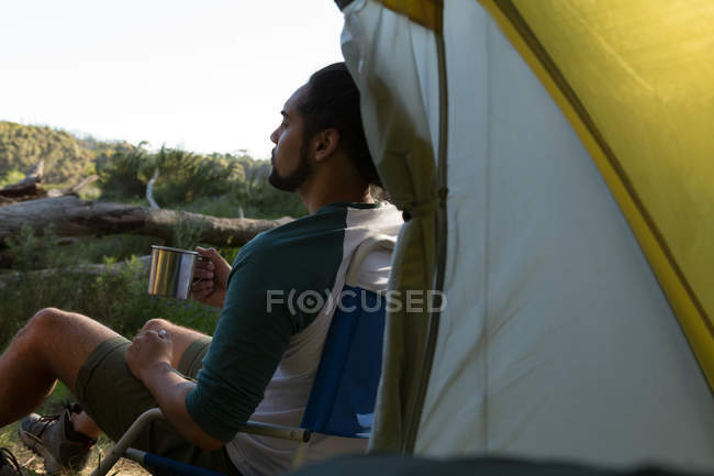 Homem tomando café perto da tenda na floresta — Fotografia de Stock