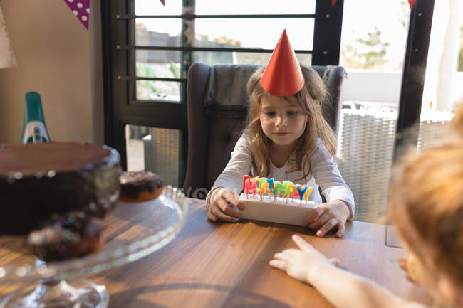 Симпатична дівчина дивиться на свічку на день народження вдома — стокове фото