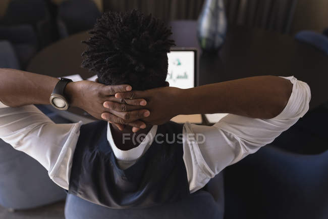 Visão traseira do empresário sentado com a mão atrás da cabeça na sala de conferências — Fotografia de Stock