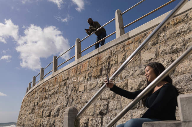 Donna sorridente che fa selfie sulle scale del lungomare — Foto stock
