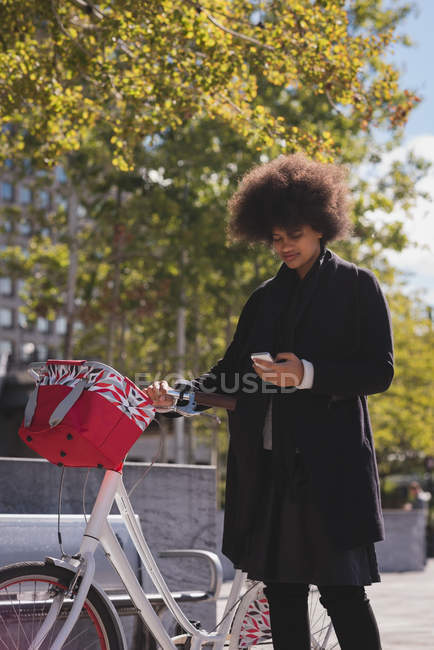 Женщина, использующая мобильный телефон в городе в солнечный день — стоковое фото