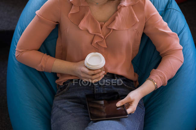Seção intermediária do executivo de negócios feminino usando tablet digital enquanto toma café — Fotografia de Stock