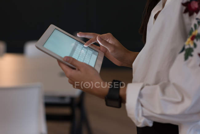 Sección media de la mujer de negocios utilizando tableta digital en la oficina - foto de stock