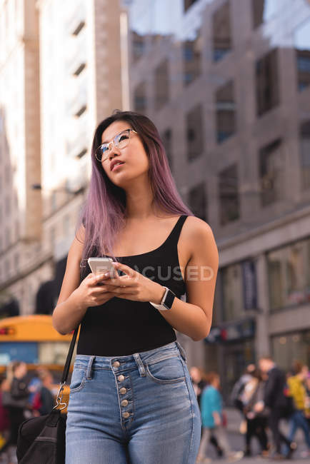 Nachdenkliche Frau benutzt Handy in der Stadt — Stockfoto