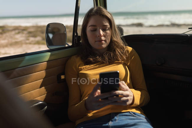 Woman using mobile phone in van on road trip — Stock Photo