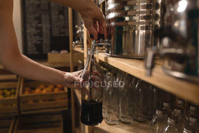 Close-up of woman filling vinegar in bottle at supermarket — Stock Photo