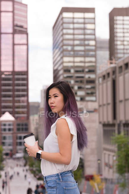 Beautiful woman holding coffee cup on street — Stock Photo