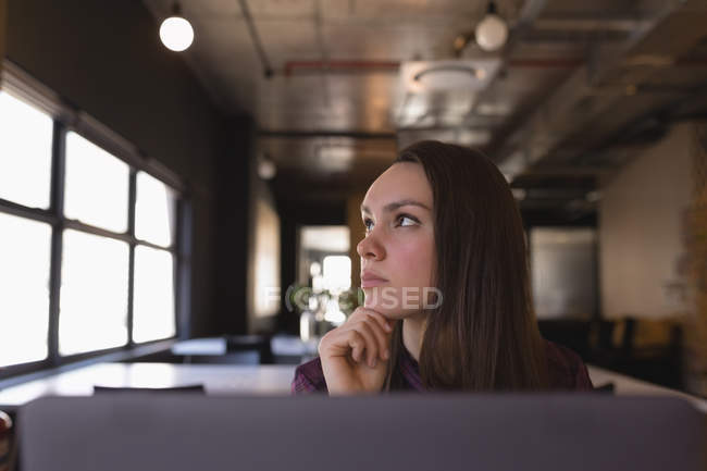Задумчивая деловая женщина сидит за столом в офисе — стоковое фото