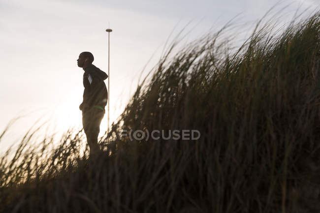 Low angle view of male athlete standing near beach — Stock Photo