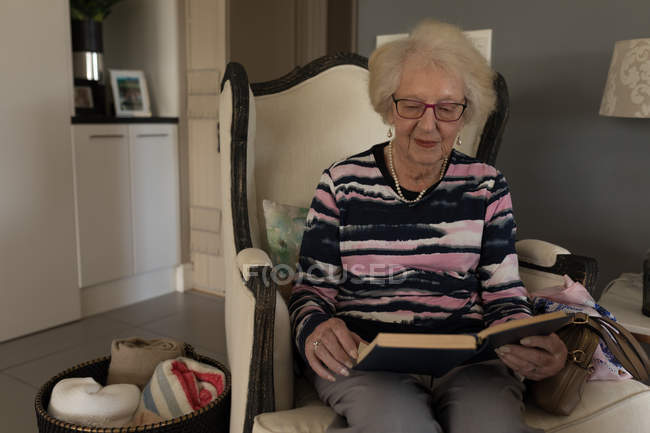 Старші жінки читання книги у вітальні на дому — стокове фото