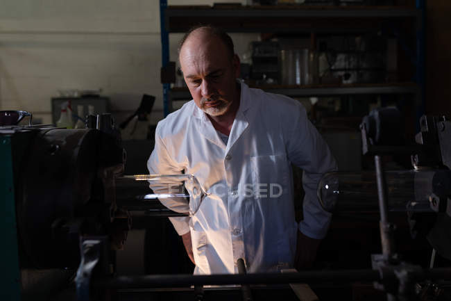 Уважний працівник чоловічої статі вивчає скляний продукт на заводі — стокове фото