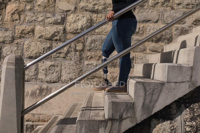 Низкая часть женщины-инвалида спускается по лестнице — стоковое фото