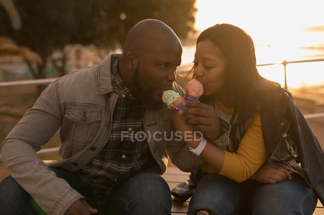Romantic couple having ice cream on promenade bench — Stock Photo