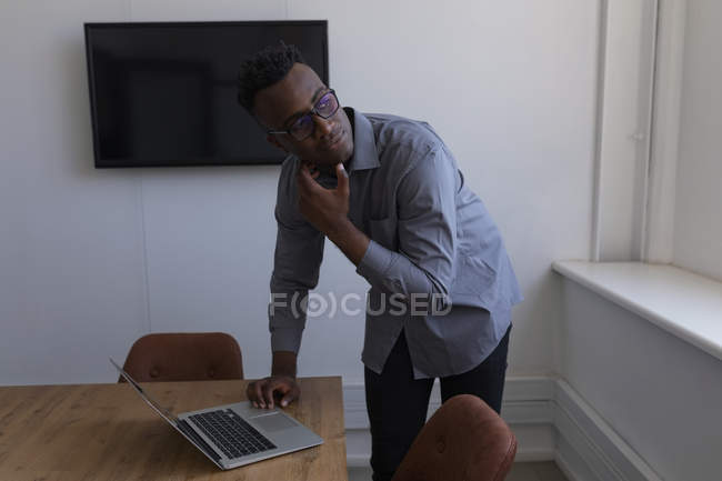 Вдумчивый мужчина, использующий ноутбук в офисе — стоковое фото
