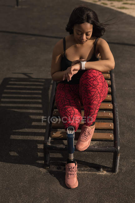 Disabled woman using smartwatch on sunny day — Stock Photo