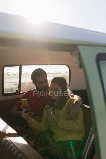 Paar diskutiert beim Kaffeetrinken auf Roadtrip am Handy — Stockfoto
