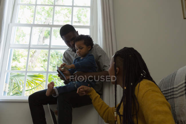 Семья с помощью мобильного телефона в гостиной на дому — стоковое фото
