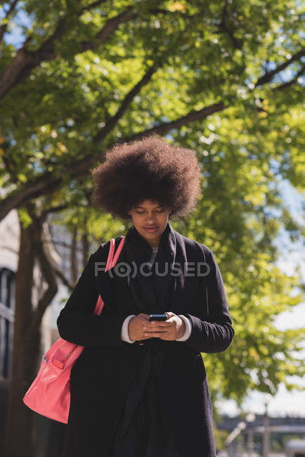 Woman using mobile in city on a sunny day — Stock Photo