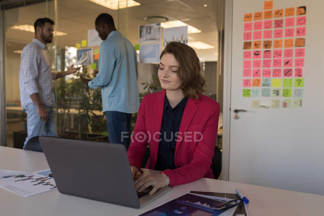 Female business executive using laptop in office — Stock Photo