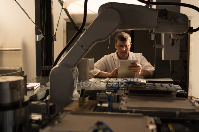 Ingeniero robótico usando tableta digital en almacén - foto de stock