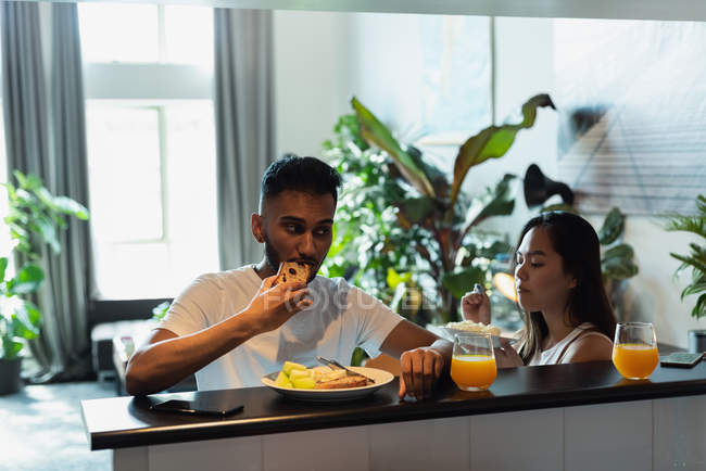 Пара, имеющая еду на рабочем столе на кухне дома — стоковое фото
